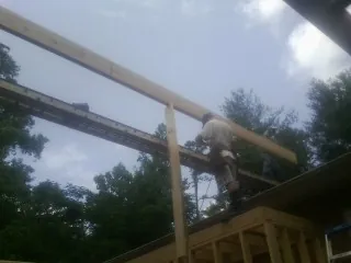 Carpenter setting a ridge beam over a new addition frame — Ice Dam Removal by Roofing Brothers in Rougemont