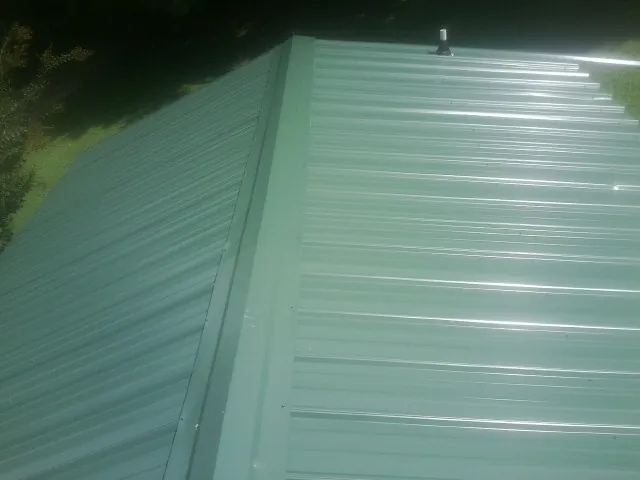 New green metal panels meeting at the ridge of a roof — Flat Roof Repair work by our crew in Rougemont