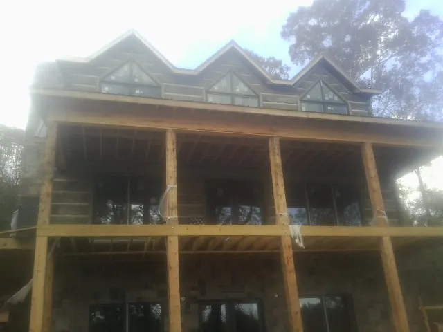 Dormers and porch framing on a large log home under construction — Roof Coating work by our crew in Rougemont