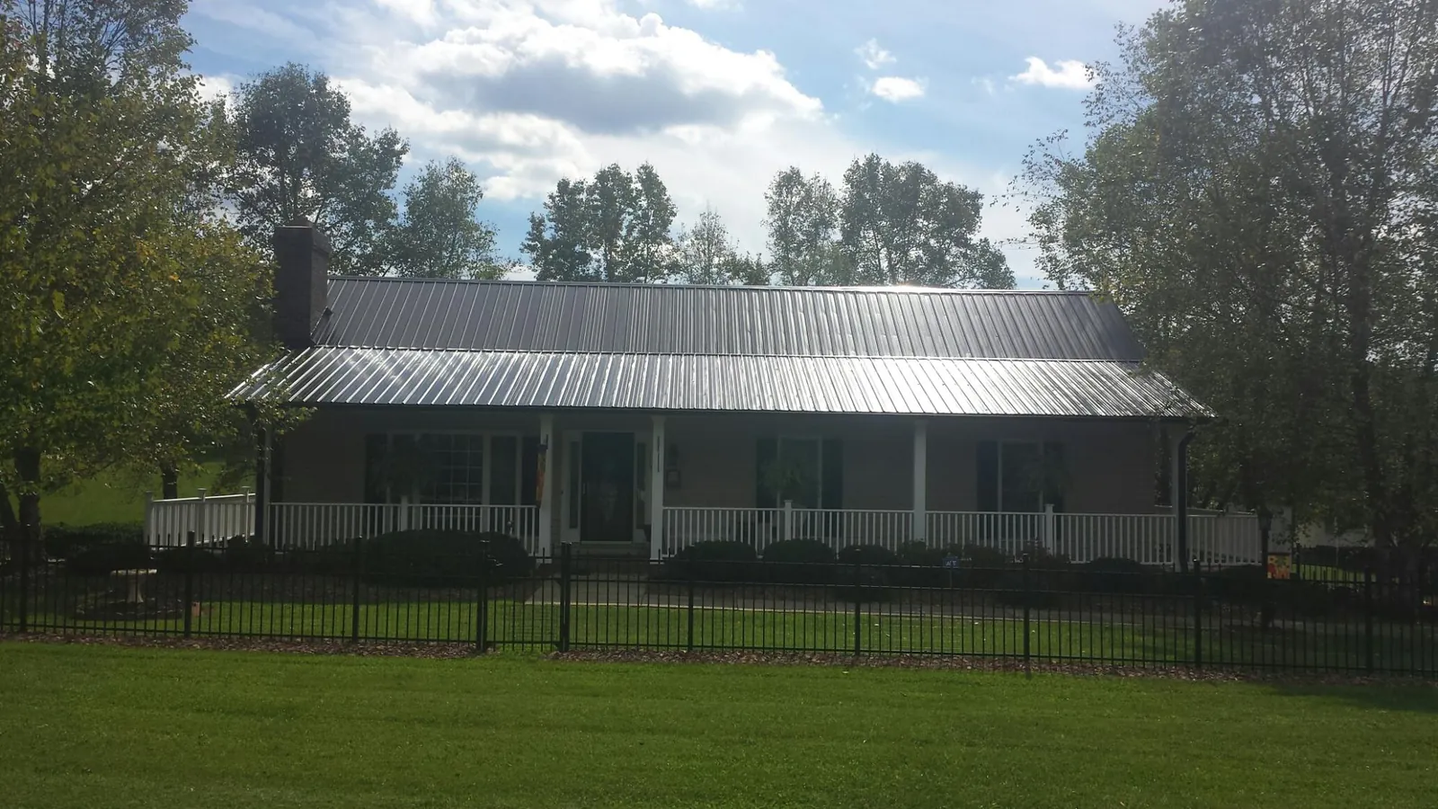 Gray metal roof on a brick ranch with a full width front porch — Gutter Guard Installation work by our crew in Rougemont