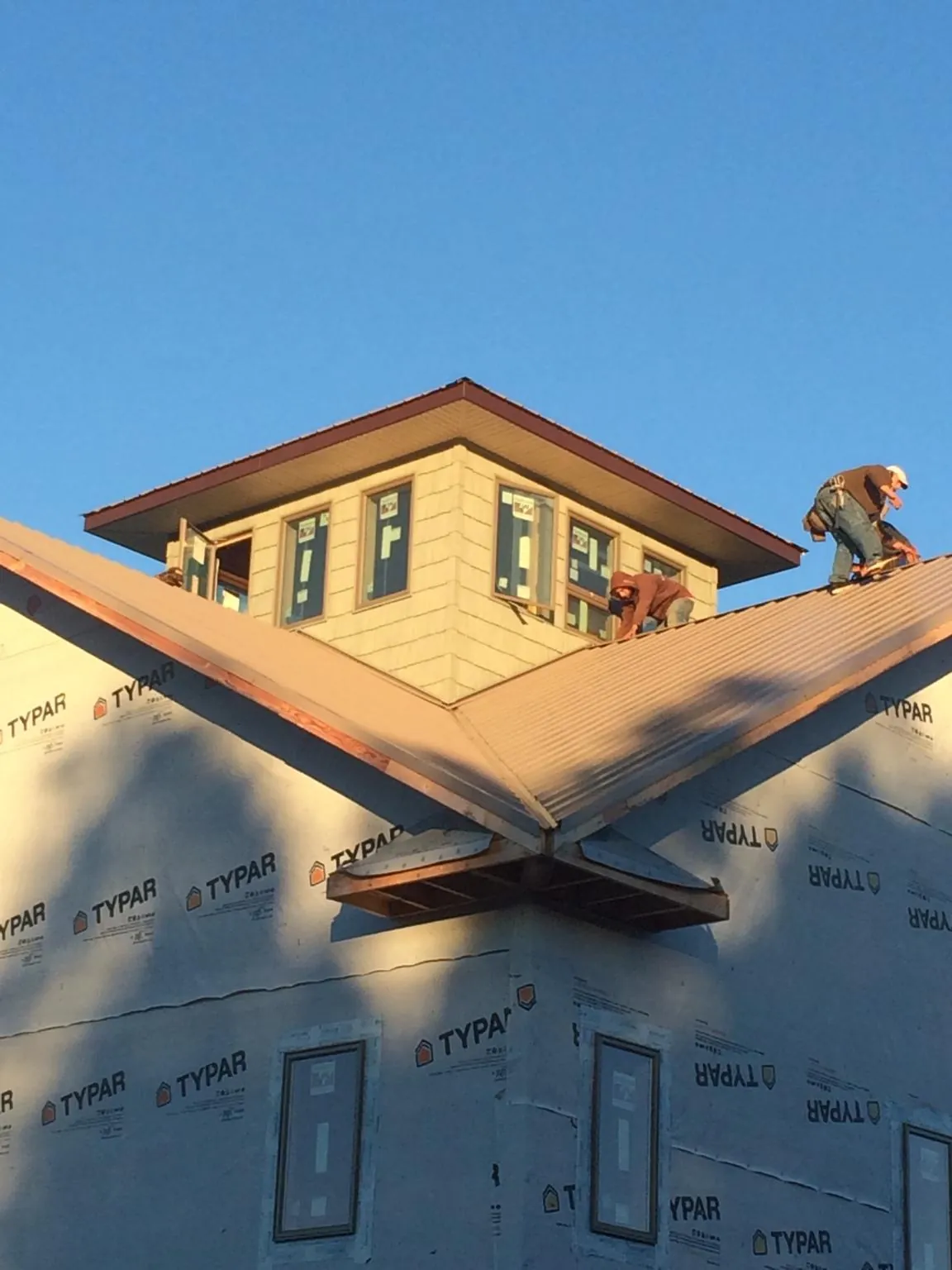Roofers working around a rooftop cupola on a new metal roof at sunset — Roof Waterproofing in Rougemont by Roofing Brothers